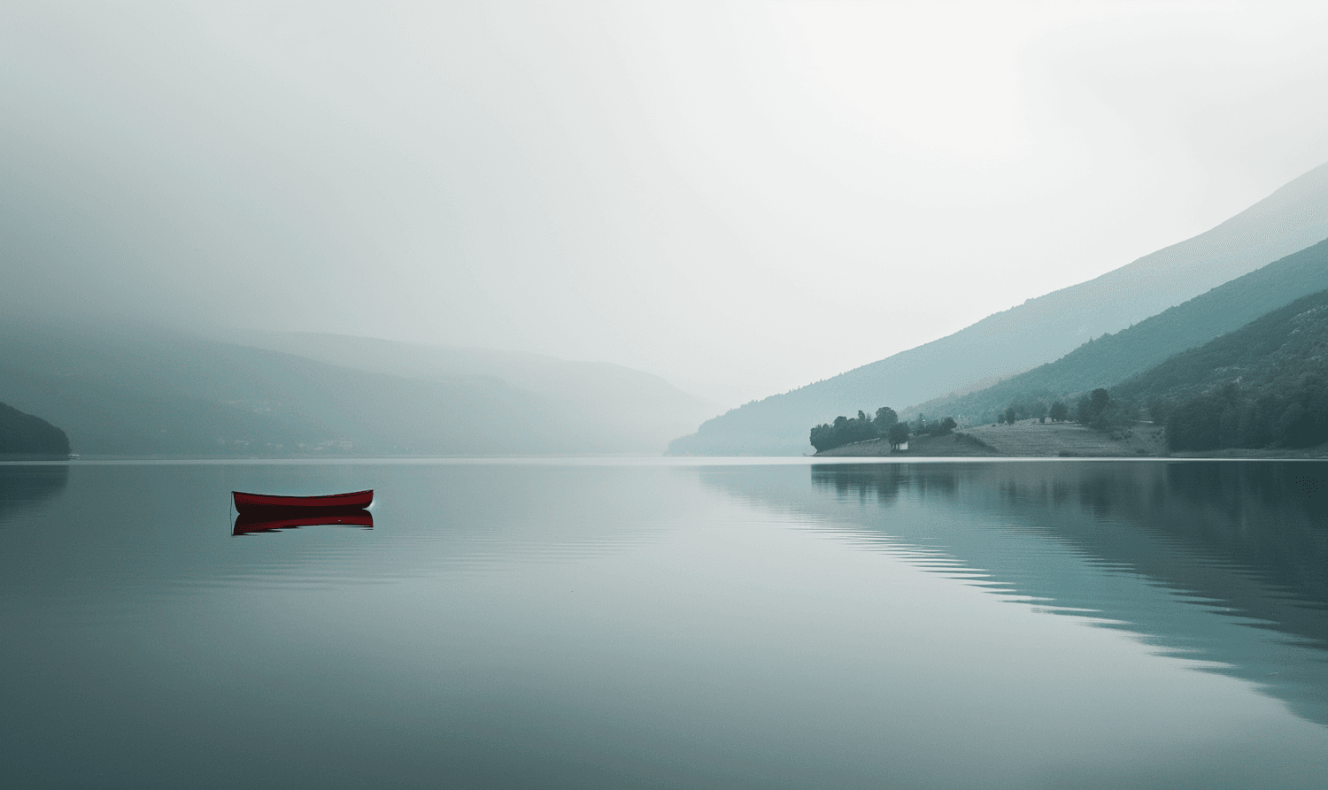 A red canoe on a misty lake at first light